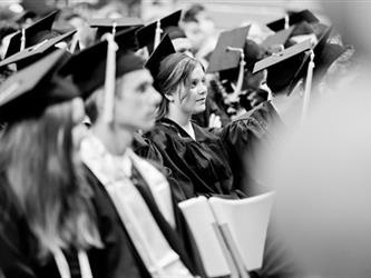 Students in black in white in cap and gown
