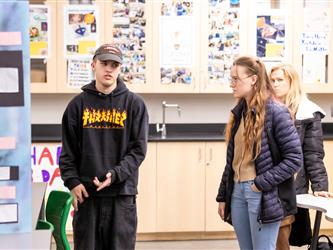 3 Students are interacting with each other in a class