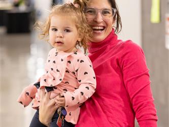A staff member is holding their baby with a smile