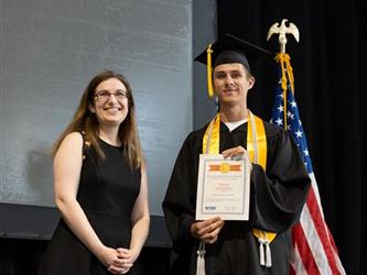Graduate with certificate posing with staff