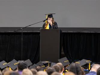 Graduate speaking on stage at podium