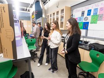 Two students are engaging with the VP at their display