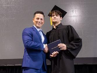 Principal posing with graduating senior