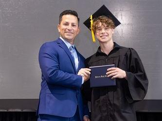 Principal posing with graduating senior