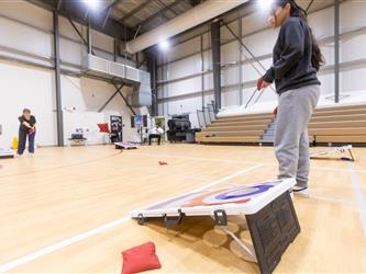 Two students playing cornhole game