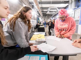 Woman is signing a document for two AP literature students at their table