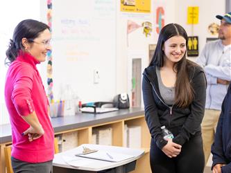 A teacher and student are seen laughing in a conversation