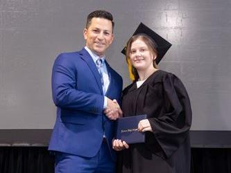 Principal posing with graduating senior