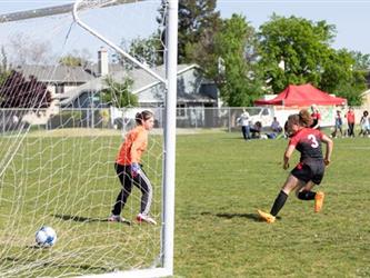 Soccer player shooting goal on goalie