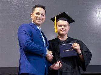 Principal posing with graduating senior