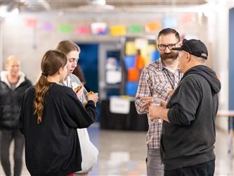 Two staff members are conversing with two students in the hallway