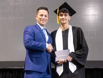 Principal posing with graduating senior