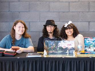 3 students are posed at their display table