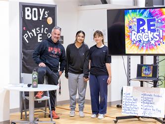 P.E Teacher and two students standing in front of T.V display