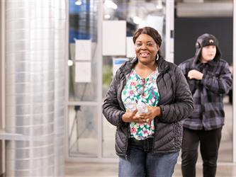 A woman is carrying two water bottles in the school hallway