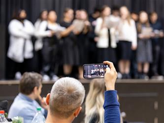 Person taking photo oh students singing on stage