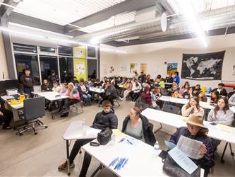 Parents and students gathered in a classroom sat at tables