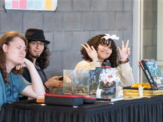 3 students are posed at their display table