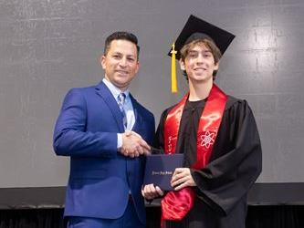 Principal posing with graduating senior
