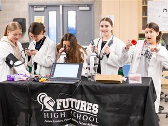 5 students are posing with science tools at their display