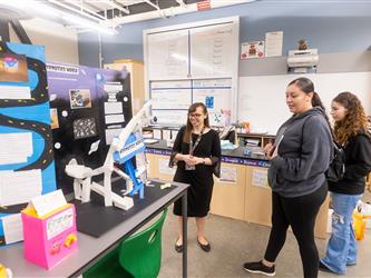 A teacher excitedly looks at a students display