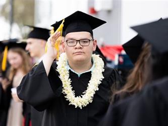Student with lei giving a salute