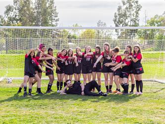 Girls soccer team standing around coach