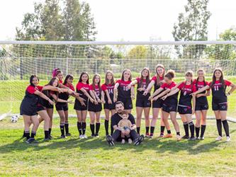 Girls soccer team standing around coach