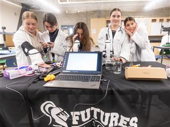 5 students are posing with science tools at their display
