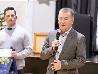 Man speaking into mic, man in background