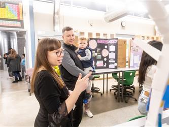 Two parents carrying a baby are exploring the table displays