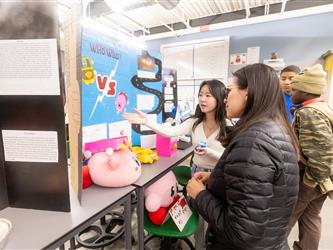 A student is engaging with GCC staff about a cardboard display of Kirby