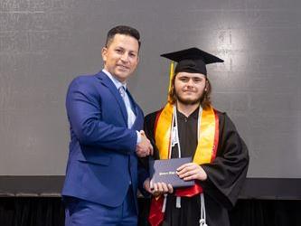 Principal posing with graduating senior
