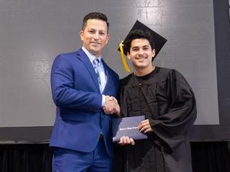 Principal posing with graduating senior