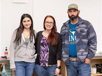 A student and two adults are pictured together in a class