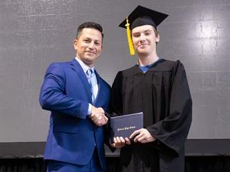 Principal posing with graduating senior