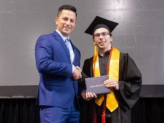 Principal posing with graduating senior
