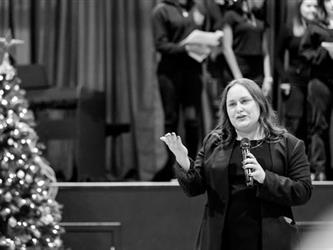 Woman speaking to families on microphone in black and white