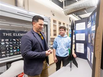 The principal is looking at a students project