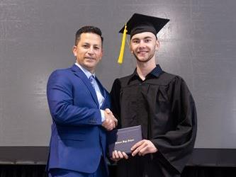 Principal posing with graduating senior