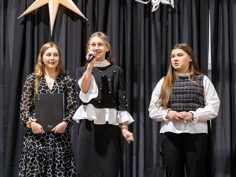 Three students on stage speaking into microphone