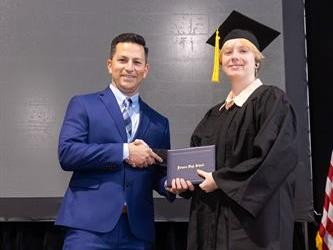 Principal posing with graduating senior