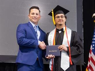 Principal posing with graduating senior