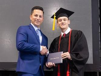 Principal posing with graduating senior