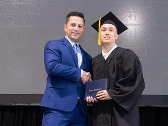 Principal posing with graduating senior