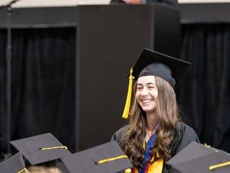 Student standing for recognition, man at podium speaks