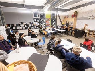 Some students and their families are sat down in a classroom