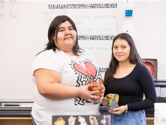 Two students are holding their pottery creations