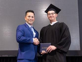 Principal posing with graduating senior