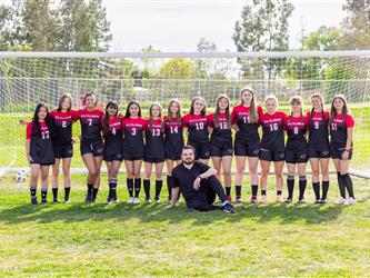 Girls soccer team standing around coach